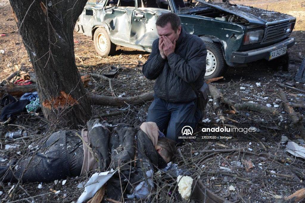 一名男子在一具尸体附近哀悼，因为空袭破坏了乌克兰哈尔科夫郊外的公寓大楼